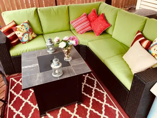 Lime-green sectional sofa with colorful pillows around a black coffee table on a red patterned rug