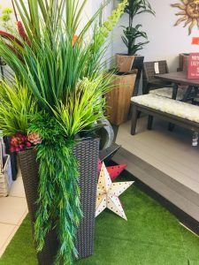 Decorative potted plants and a star ornament in a reception area with green artificial grass flooring