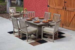 Outdoor patio dining set with cushioned chairs and a table set for a meal beside a red wall and wooden doors