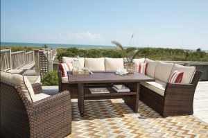 Outdoor patio seating with wicker sectional, wooden coffee table, and ocean view
