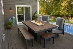 Outdoor deck with gray furniture, a rectangular dining table, and a pool in the background.