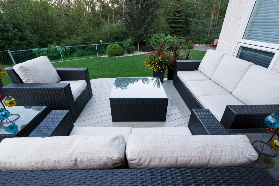 Outdoor patio seating set with gray cushions, black table, and garden view