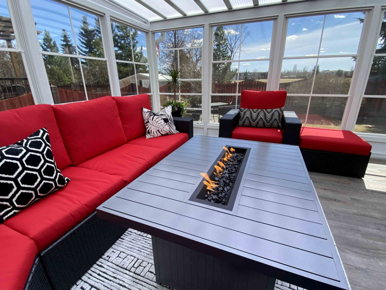 Modern screened porch with red sectional, black fire table, and outdoor lounge chairs