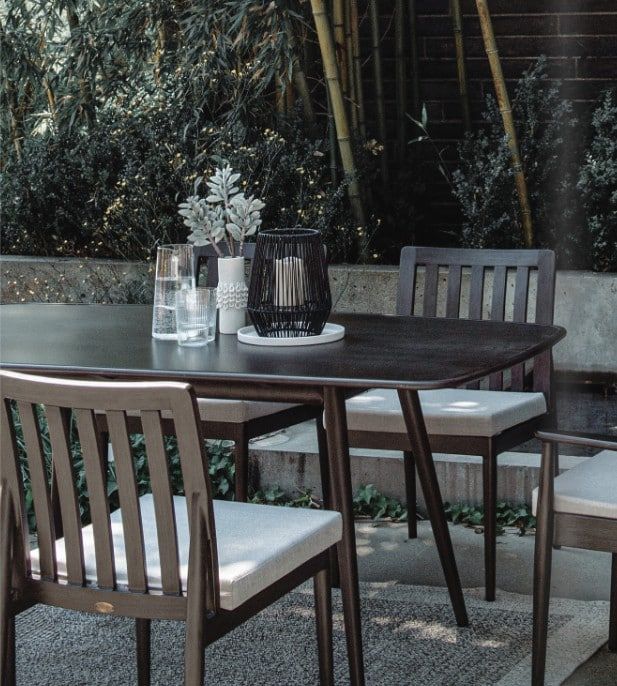 Outdoor café table with gray chairs, white cushions, and a black wire lantern centerpiece