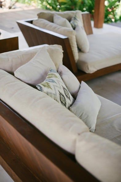 Outdoor lounge chairs with cream cushions and patterned pillows on a patio