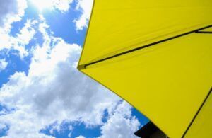 Yellow umbrella against a blue sky with white clouds