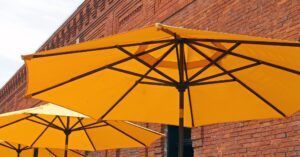 Orange patio umbrellas against a brick wall, viewed from below