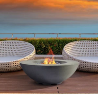 Two white wicker chairs around a gray fire bowl on a wooden deck at sunset