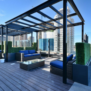 Rooftop terrace with blue outdoor seating, pergola shade, and city skyline views