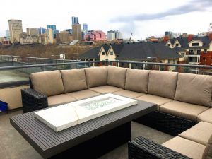 Rooftop patio with beige sectional sofa, black table, and city skyline in the background