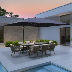 Modern patio with dining table, black umbrella, and pool beside a minimalist house at sunset