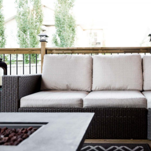 Outdoor patio with a wicker sofa, beige cushions, and a fire pit table in the foreground