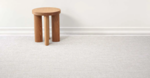 Small wooden stool on a light carpet against a white wall