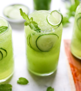Green cucumber mint drinks in glasses with cucumber slices on a bright table
