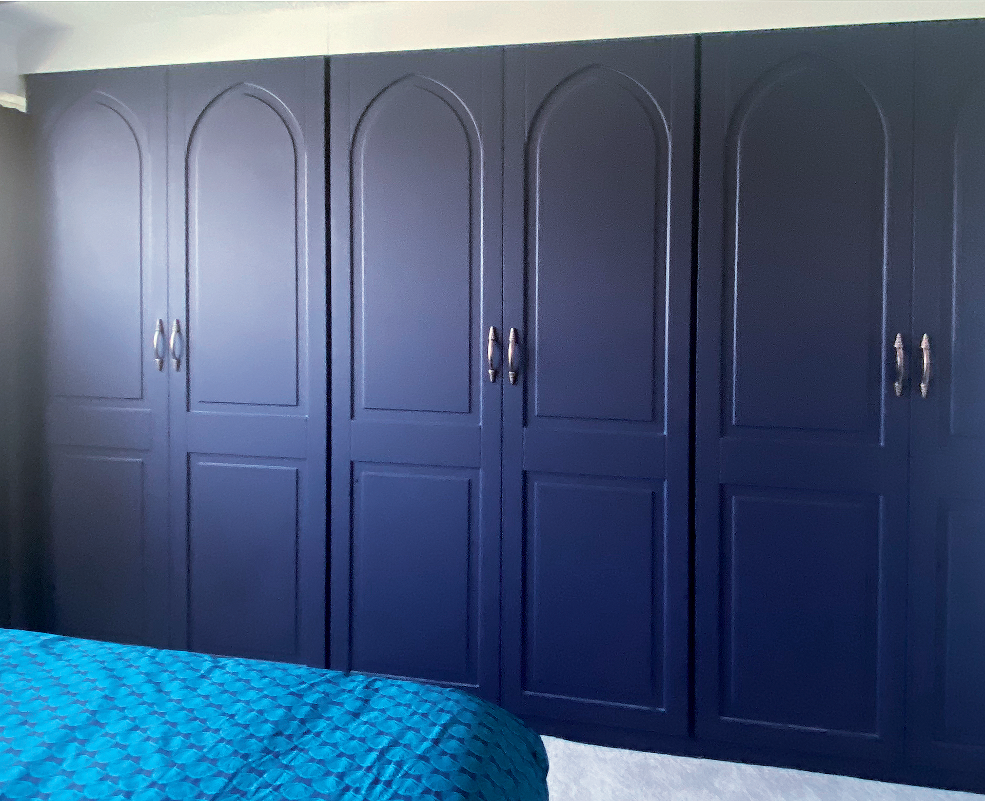 Completed wardrobes in a Marine Dark Blue, with aged bronze effect handles.