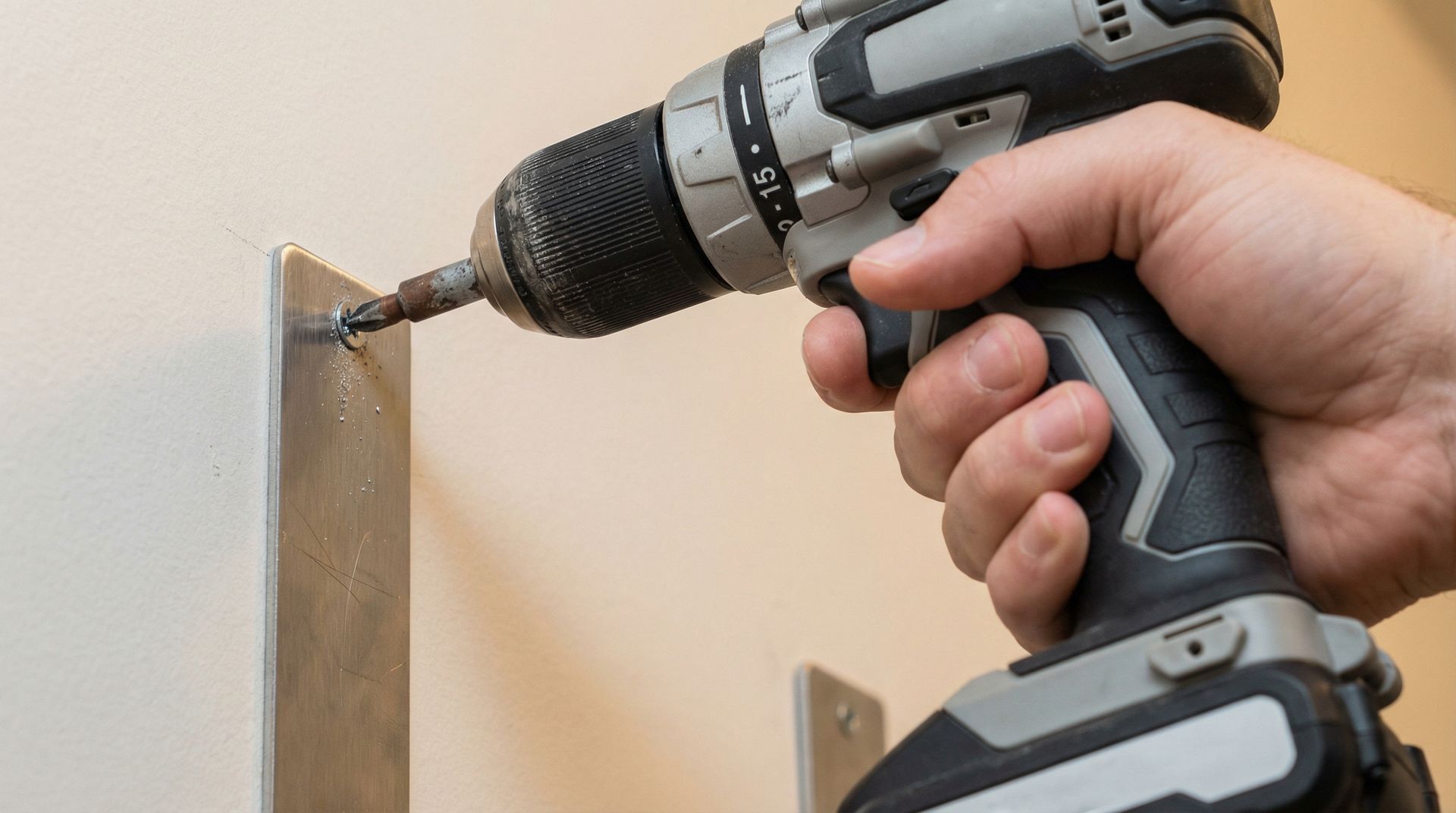 Hand fixing metal plate to the wall with a tool