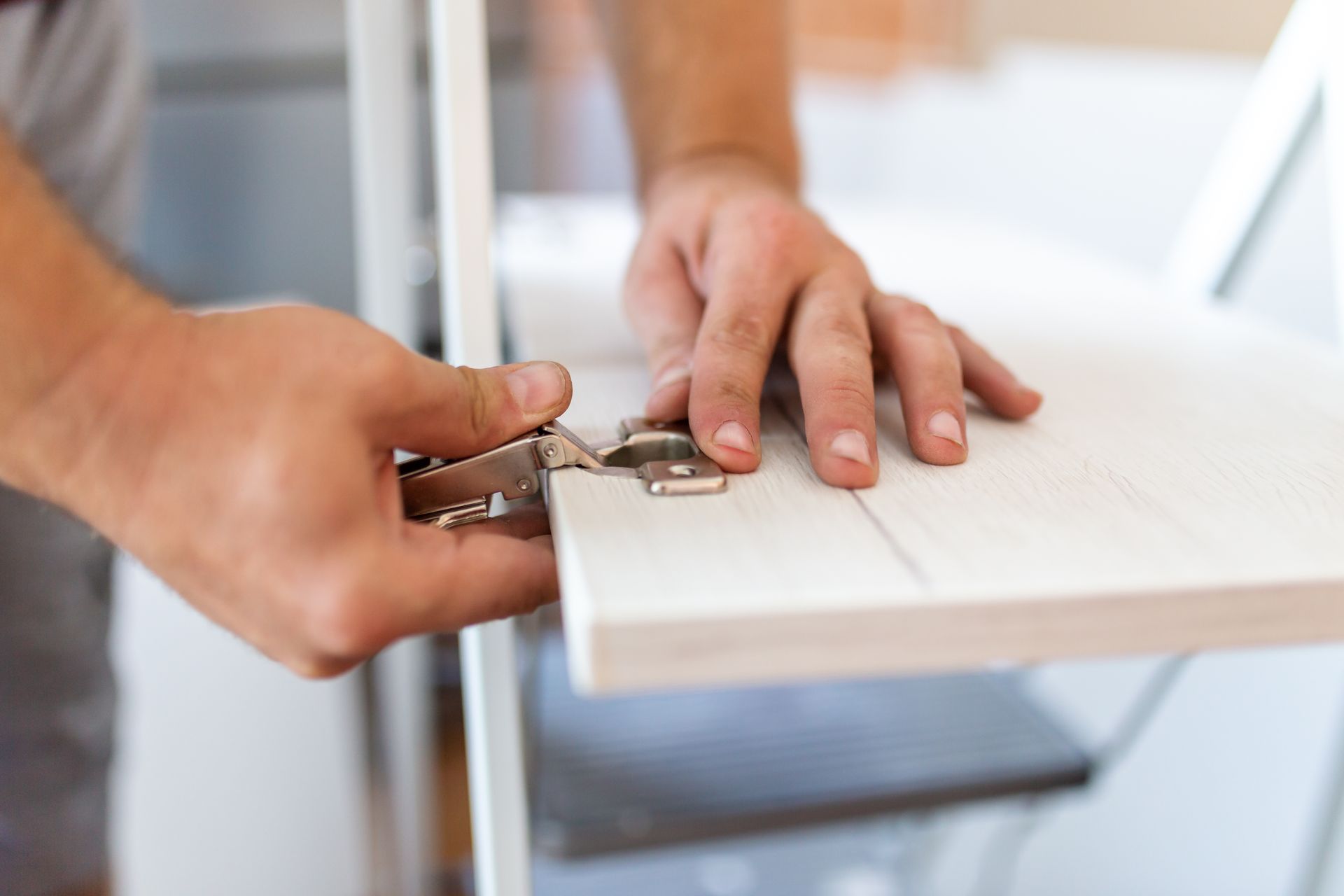 Hands fixing hinge to flat pack furniture door