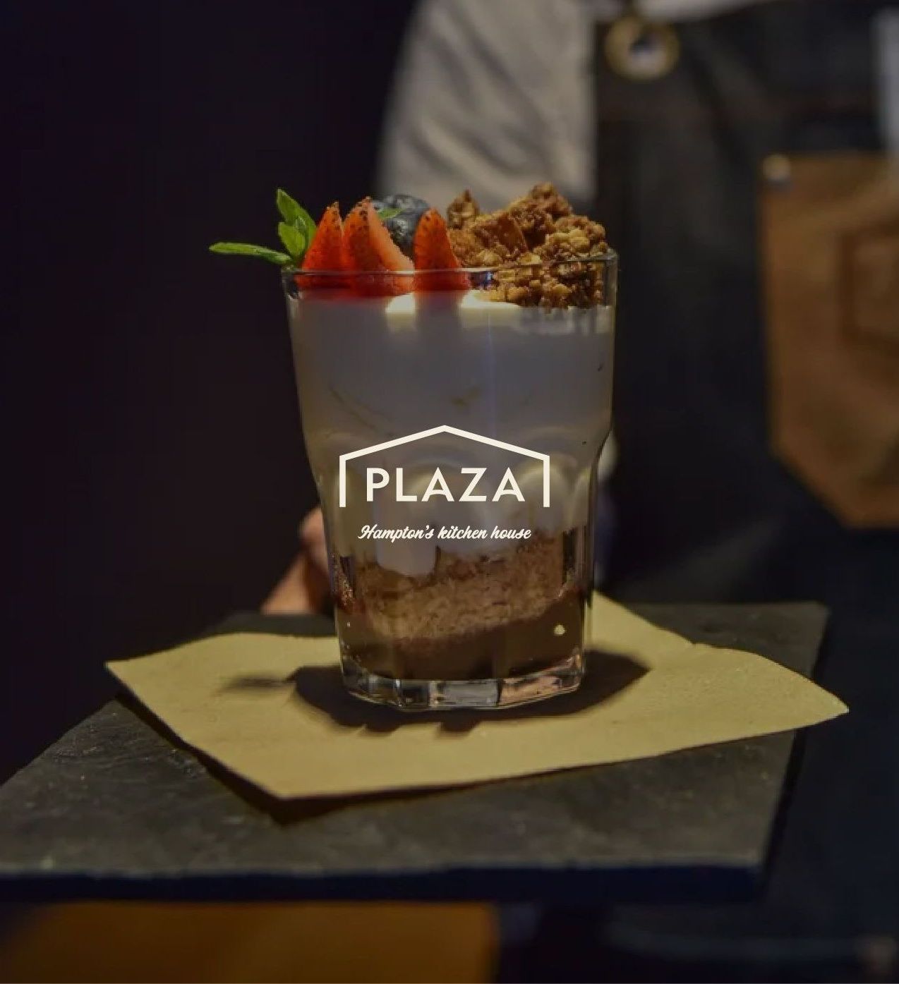 Una persona sostiene un vaso con el logo de la plaza.