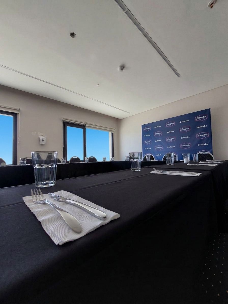 Una sala de conferencias con mesas preparadas para una reunión.