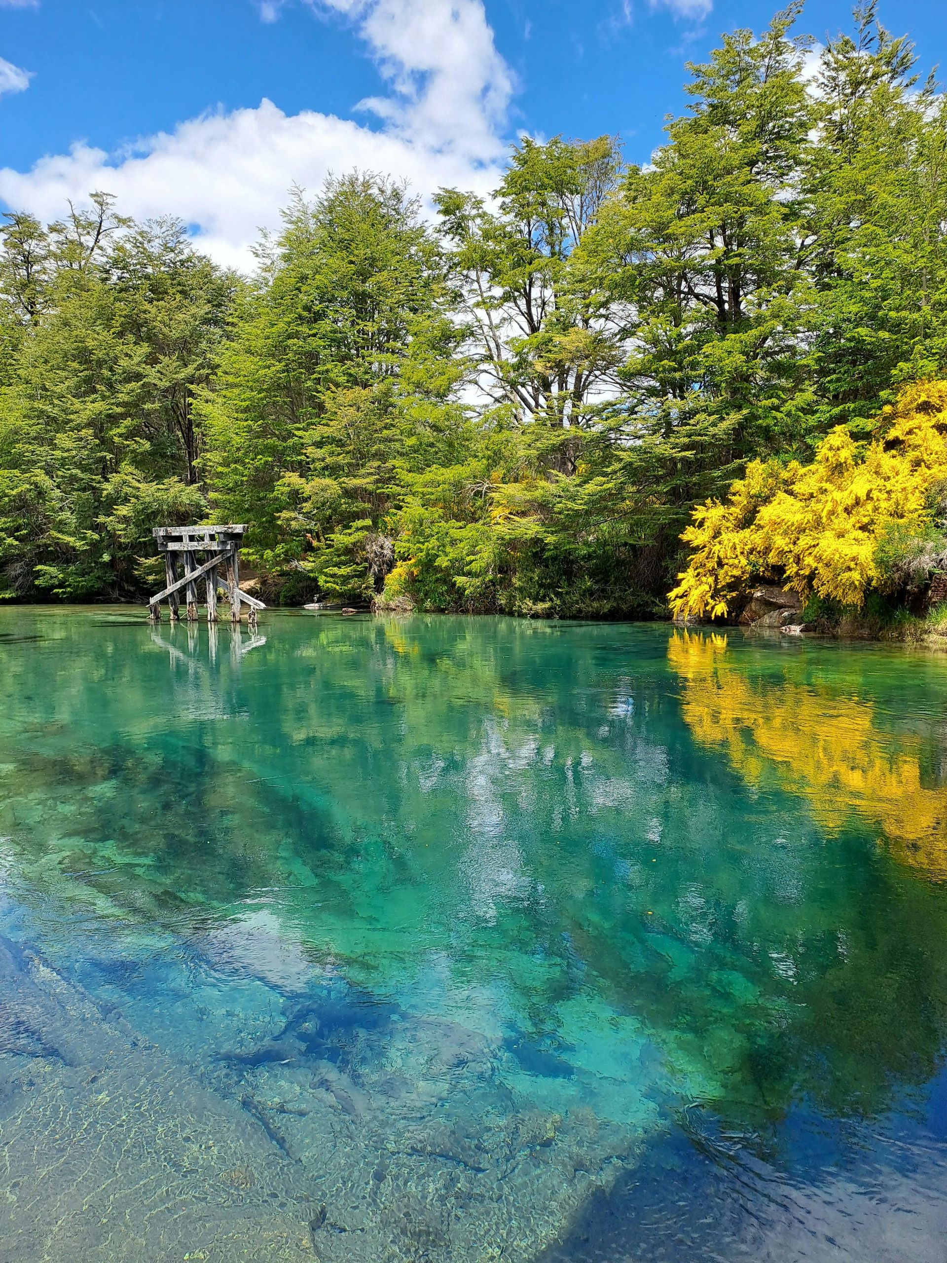 Un lago con montañas al fondo y rocas en primer plano.