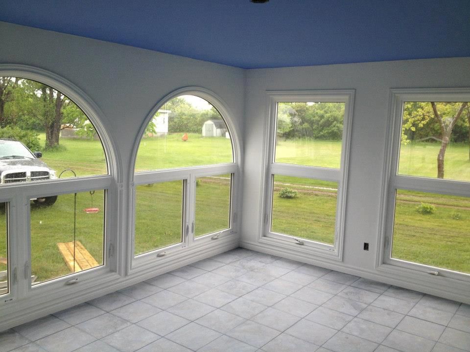 A screened in porch with arched windows and a blue ceiling