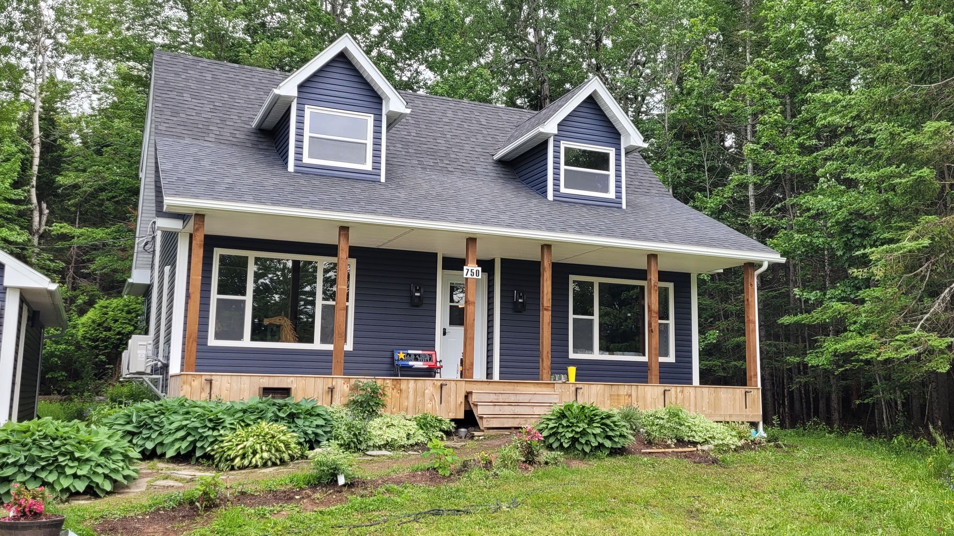 A small blue house with a porch in the middle of a forest.