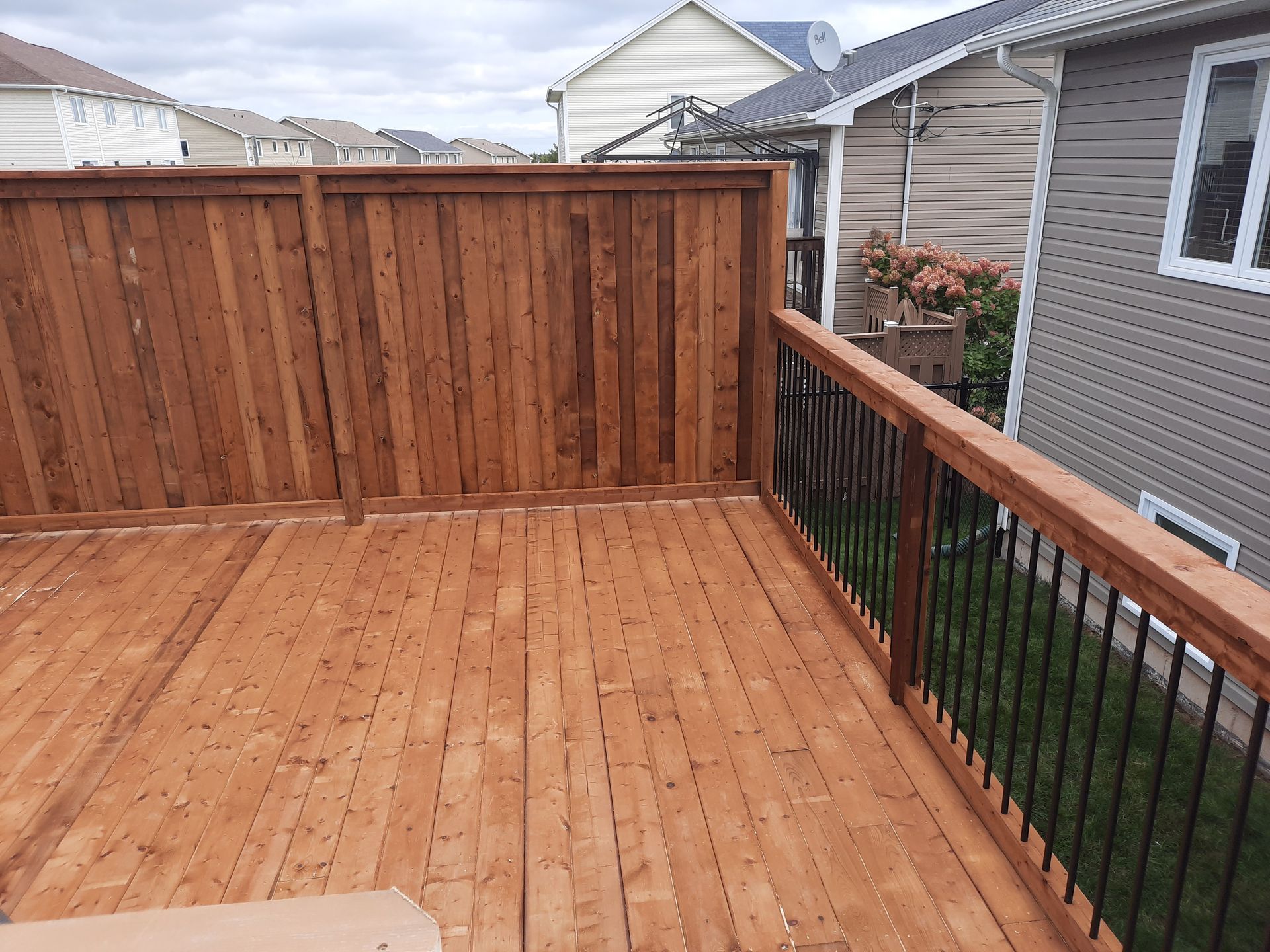 A wooden deck with a fence and railing in front of a house.