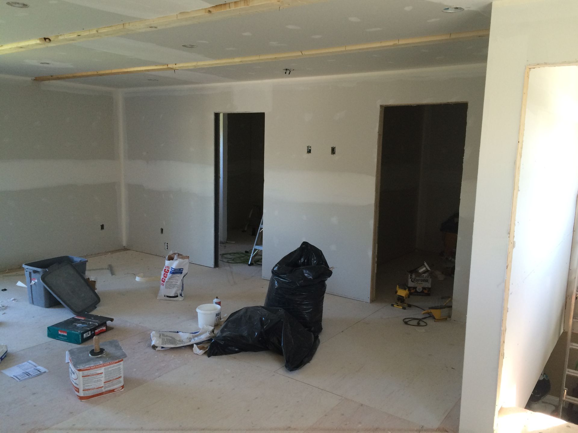 Unfinished room with drywall, open doorways, and construction debris scattered on the floor.