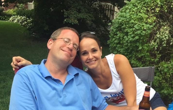 A man and a woman are posing for a picture while sitting on a bench.