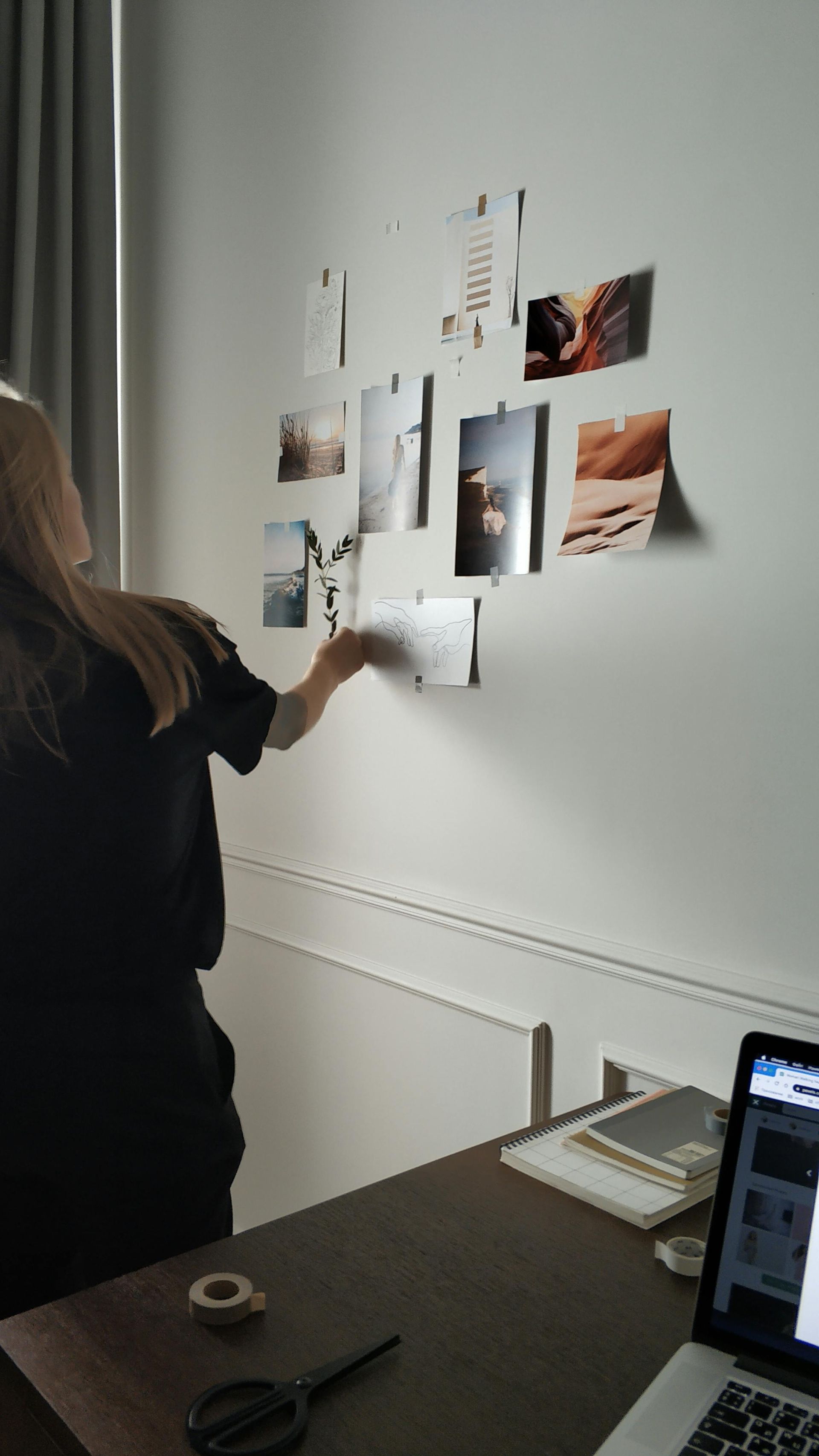 A woman is standing in front of a wall with pictures on it.