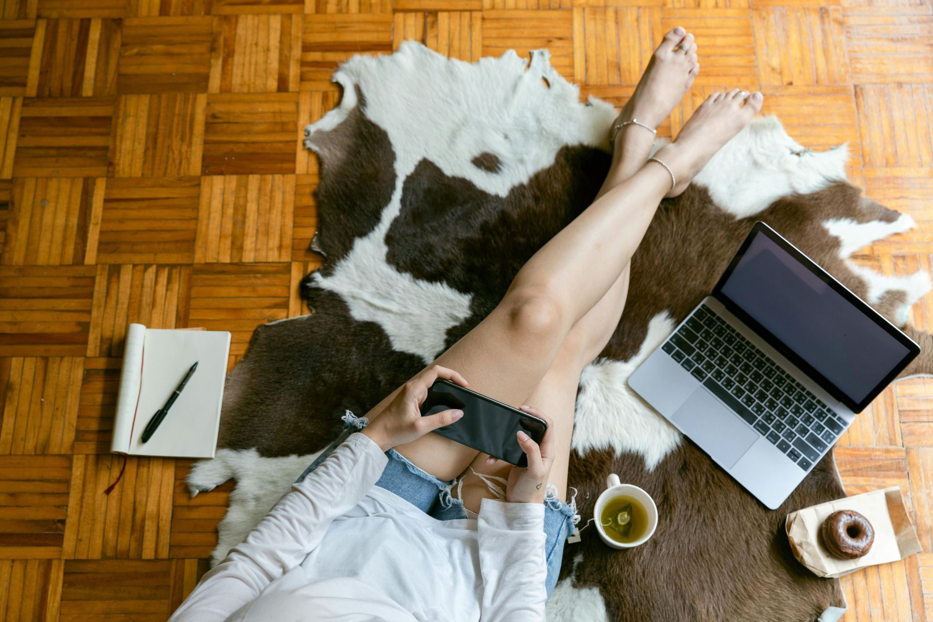 A person is typing on a laptop computer on a wooden table.