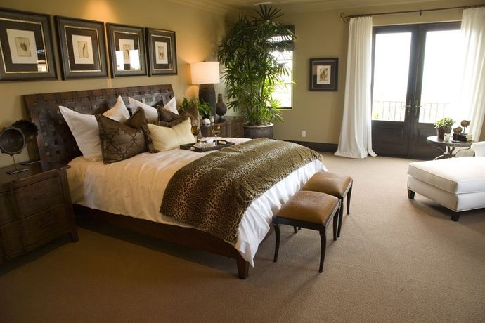 A bedroom with a large bed, two stools, and a window