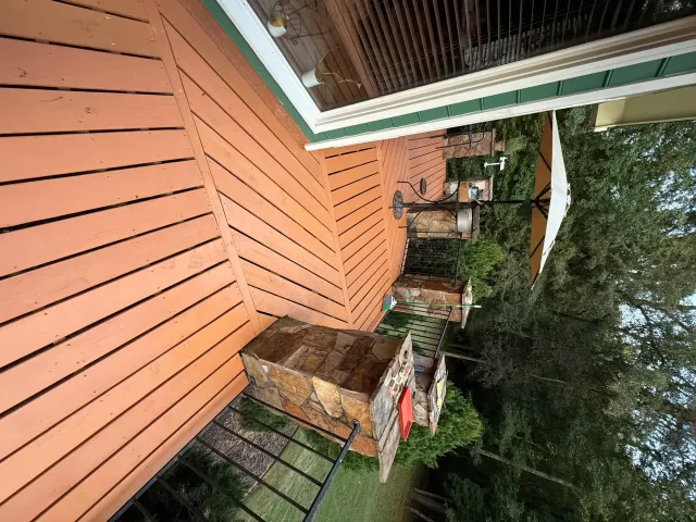 Outdoor wooden deck with brick planters and trees beside a house, viewed from above