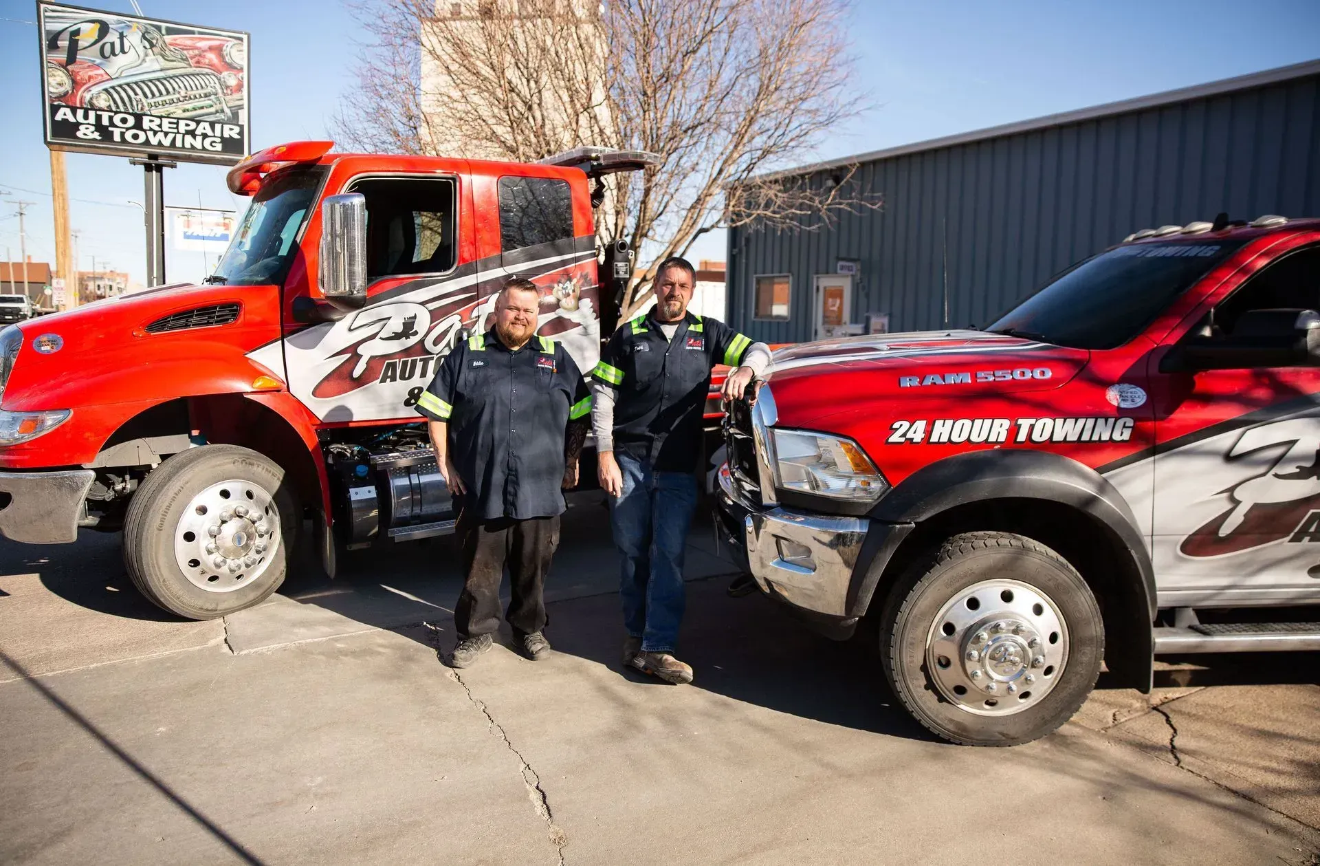 Two Technicians in front of tow trucks outside | Pat's Auto Repair & Towing