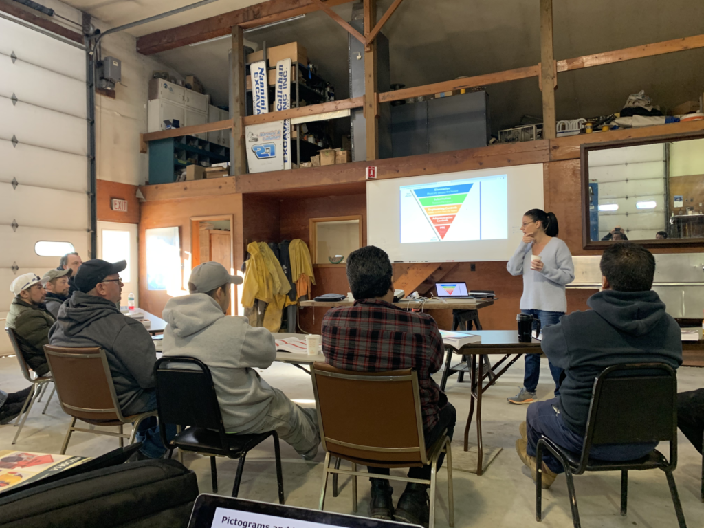 Workshop attendees seated in a loft classroom watching a speaker present a color chart.