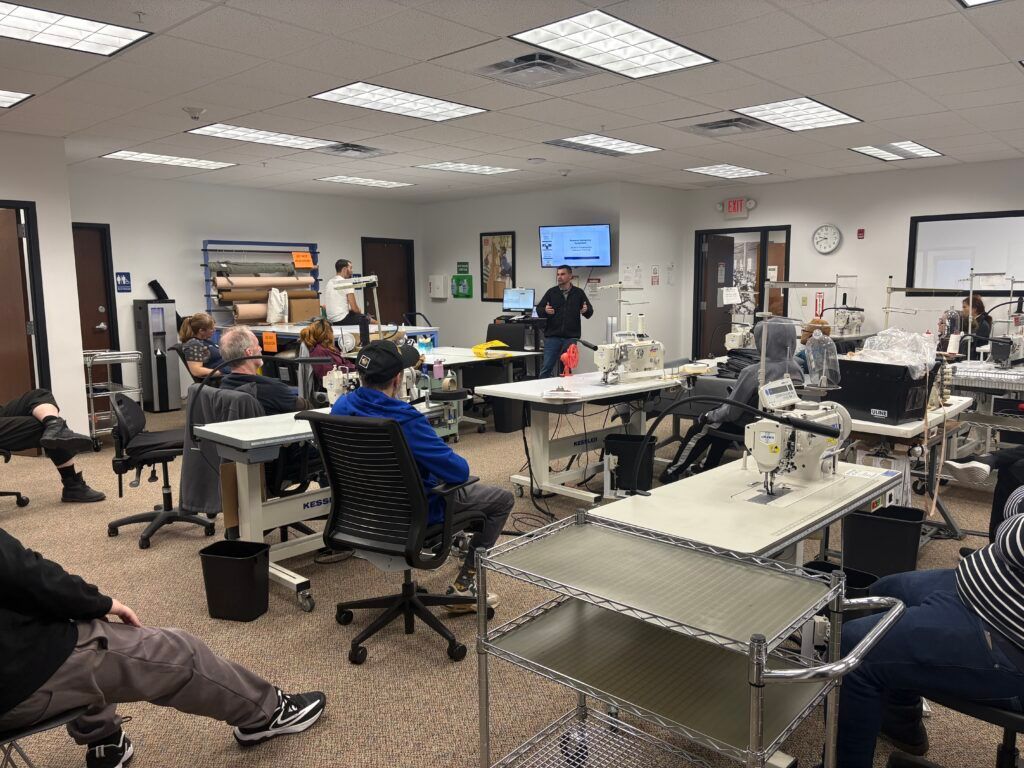 Office training room with people seated at tables and screens on the walls