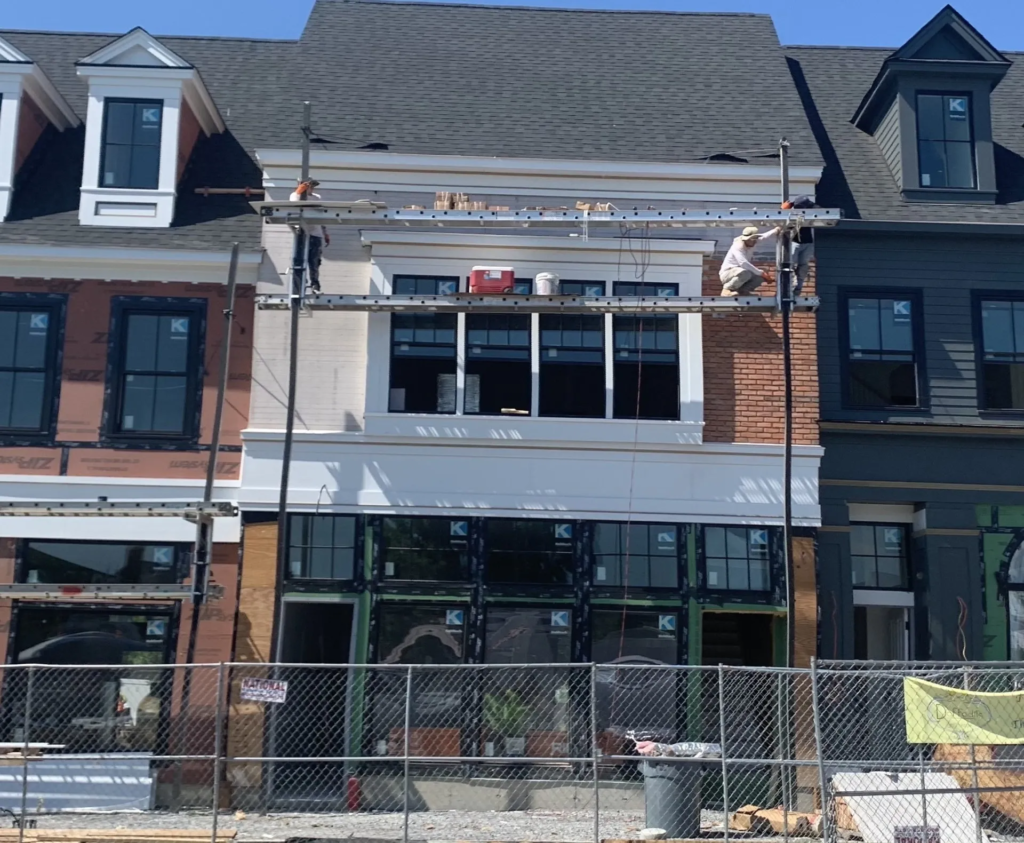 Three-story brick townhouse under construction with scaffolding and a fenced-off front entrance.