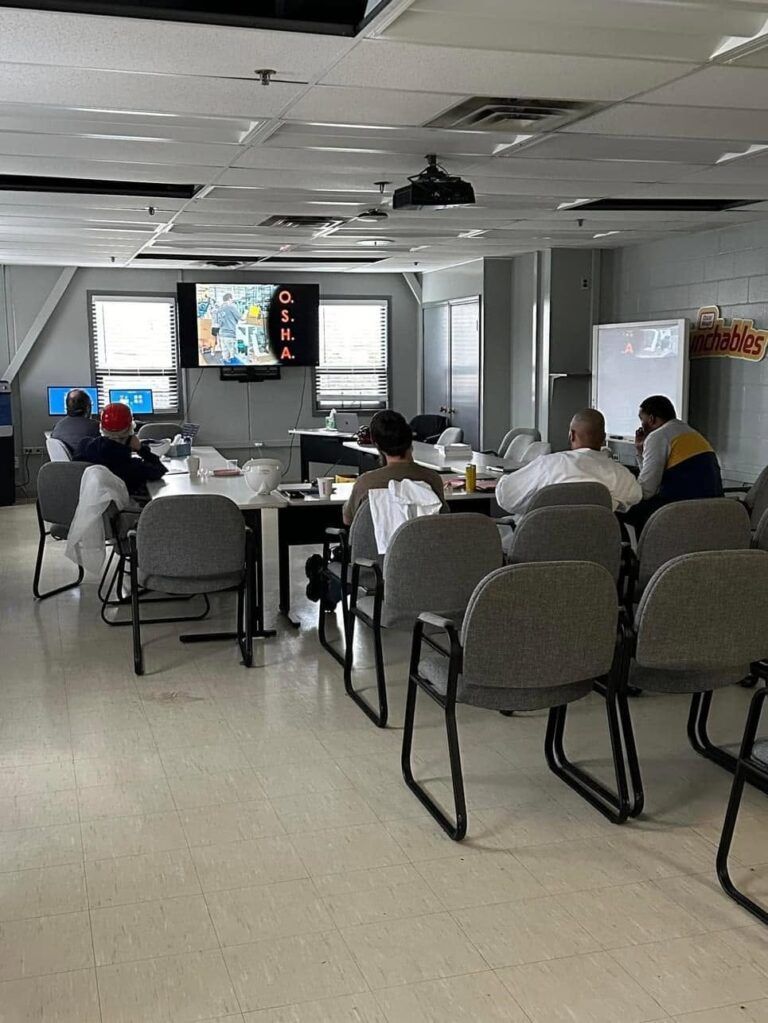 People seated in a meeting room watching a presentation on a large screen