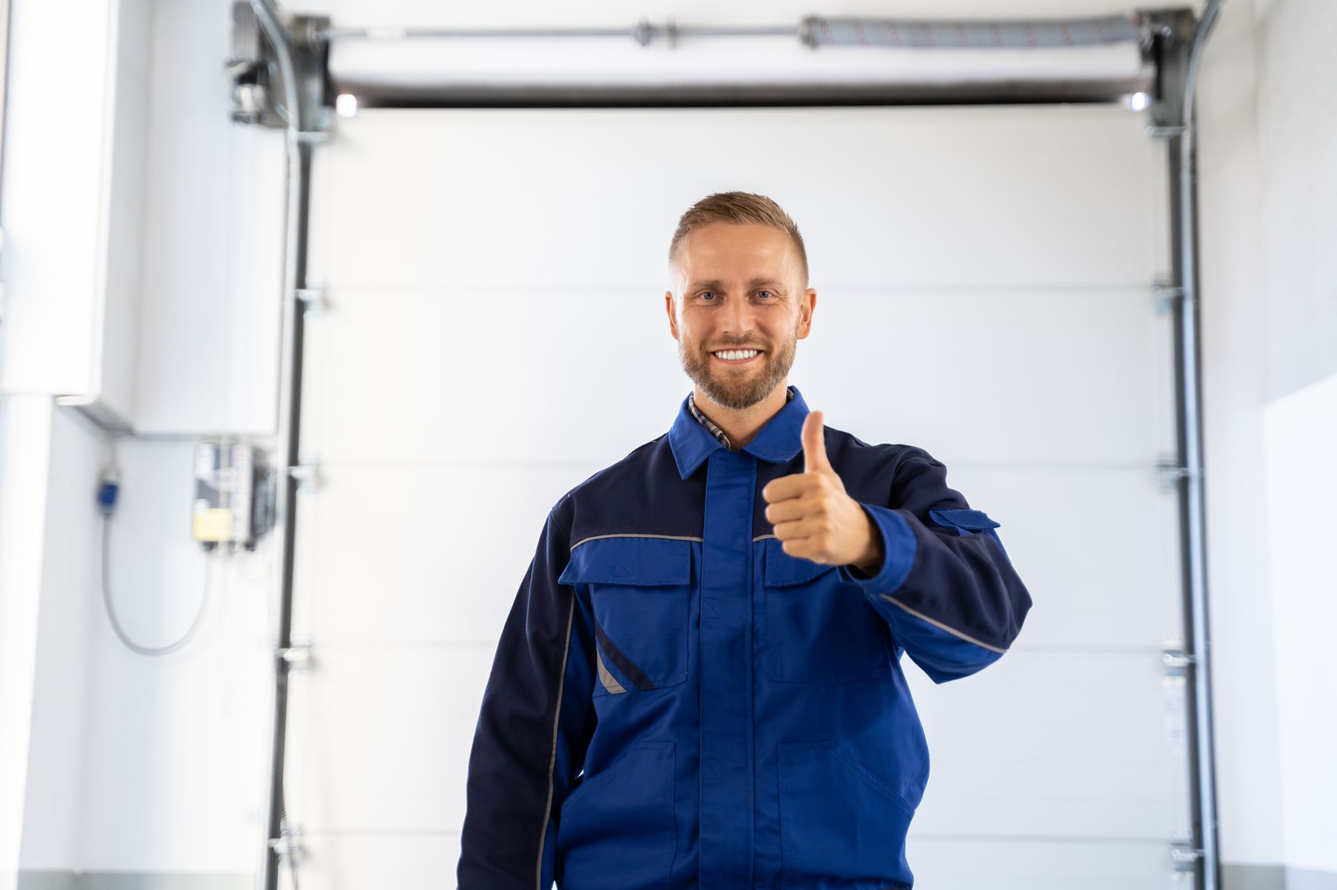A man is giving a thumbs up in front of a garage door.