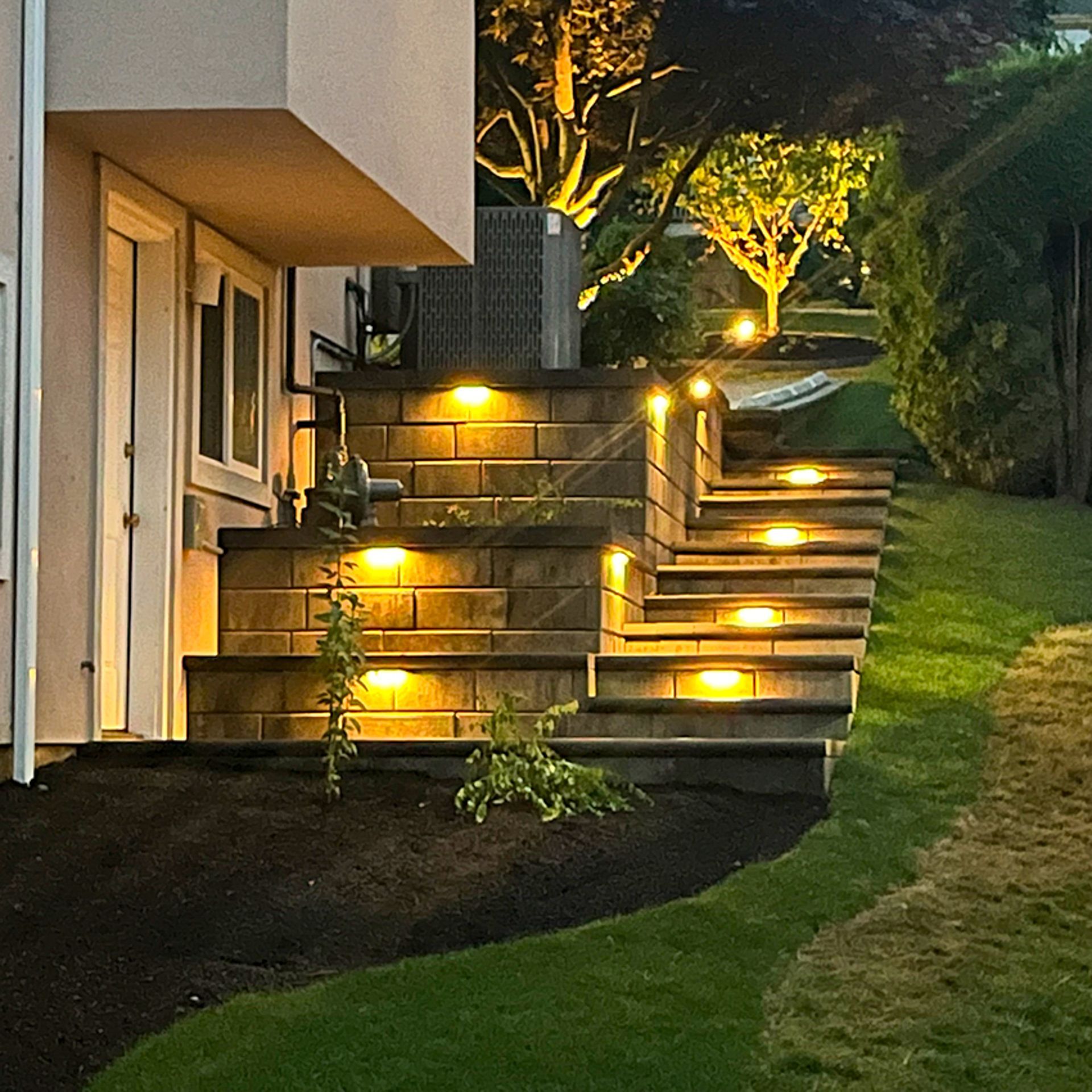 Modern home exterior with illuminated steps and landscaping at night