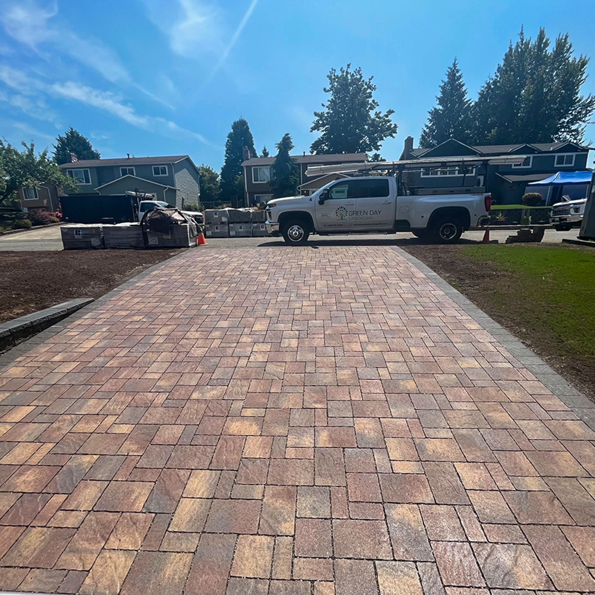 Brick driveway with a white pickup truck parked in front of houses on a sunny day.