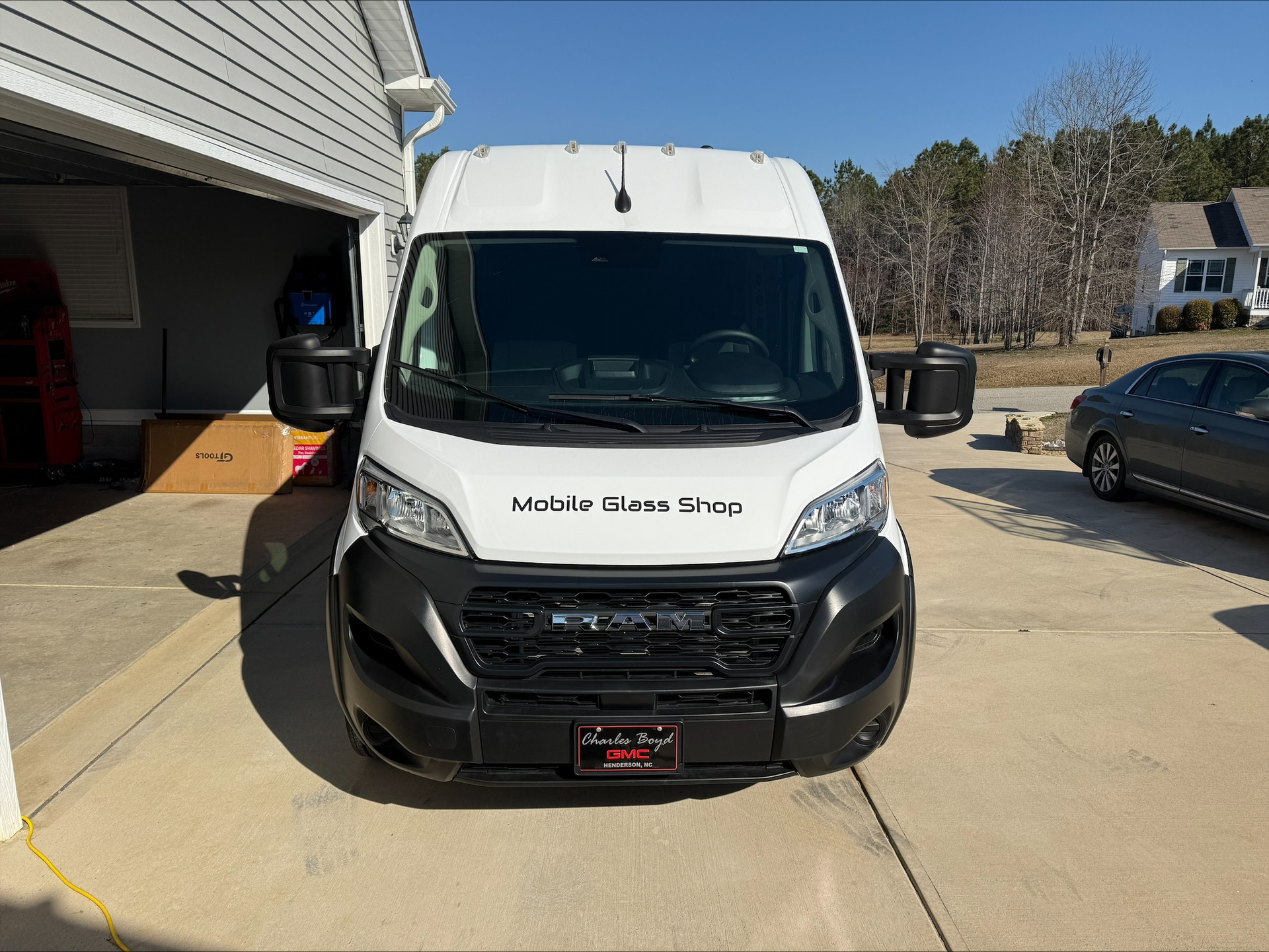 White delivery van parked in a driveway beside a garage, front view with black bumper.
