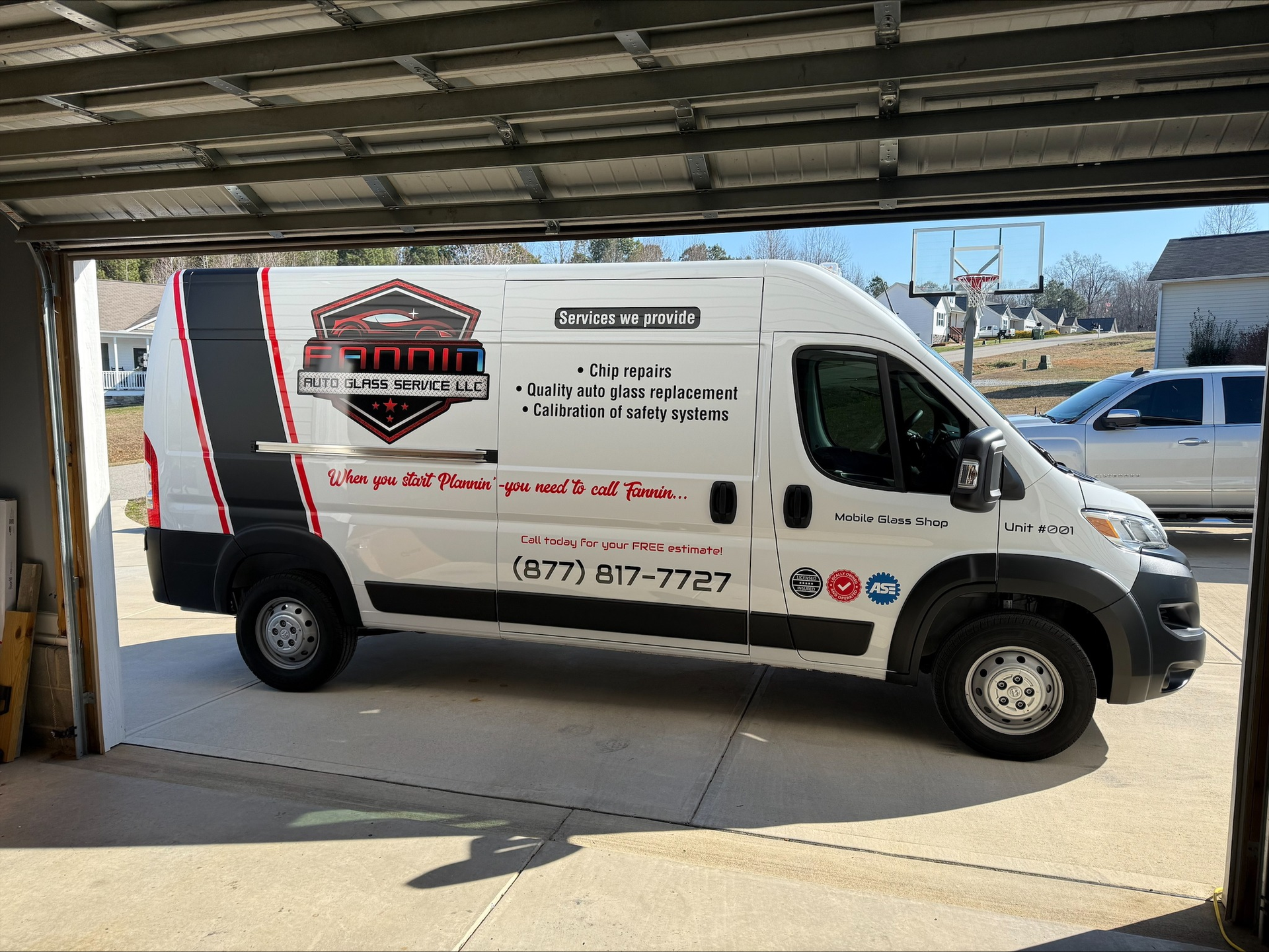 White service van with company logo parked in a garage bay, seen from the side.