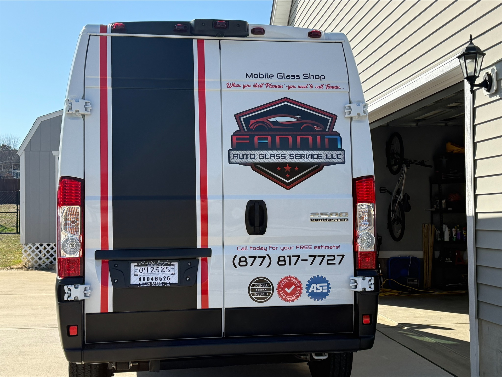White branded service van with red and black stripes parked by a garage door