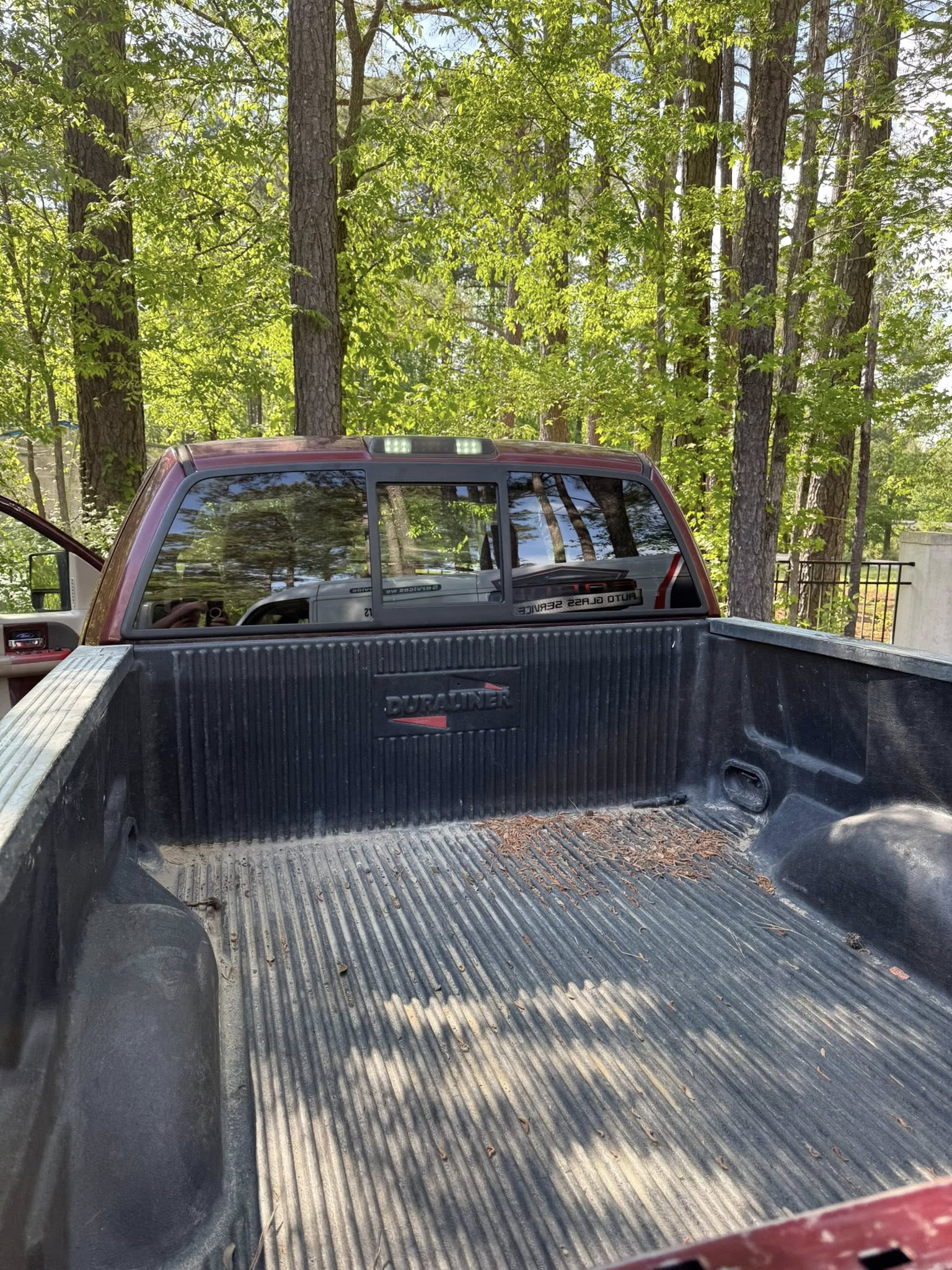 View from truck bed toward rear window in a wooded campsite area