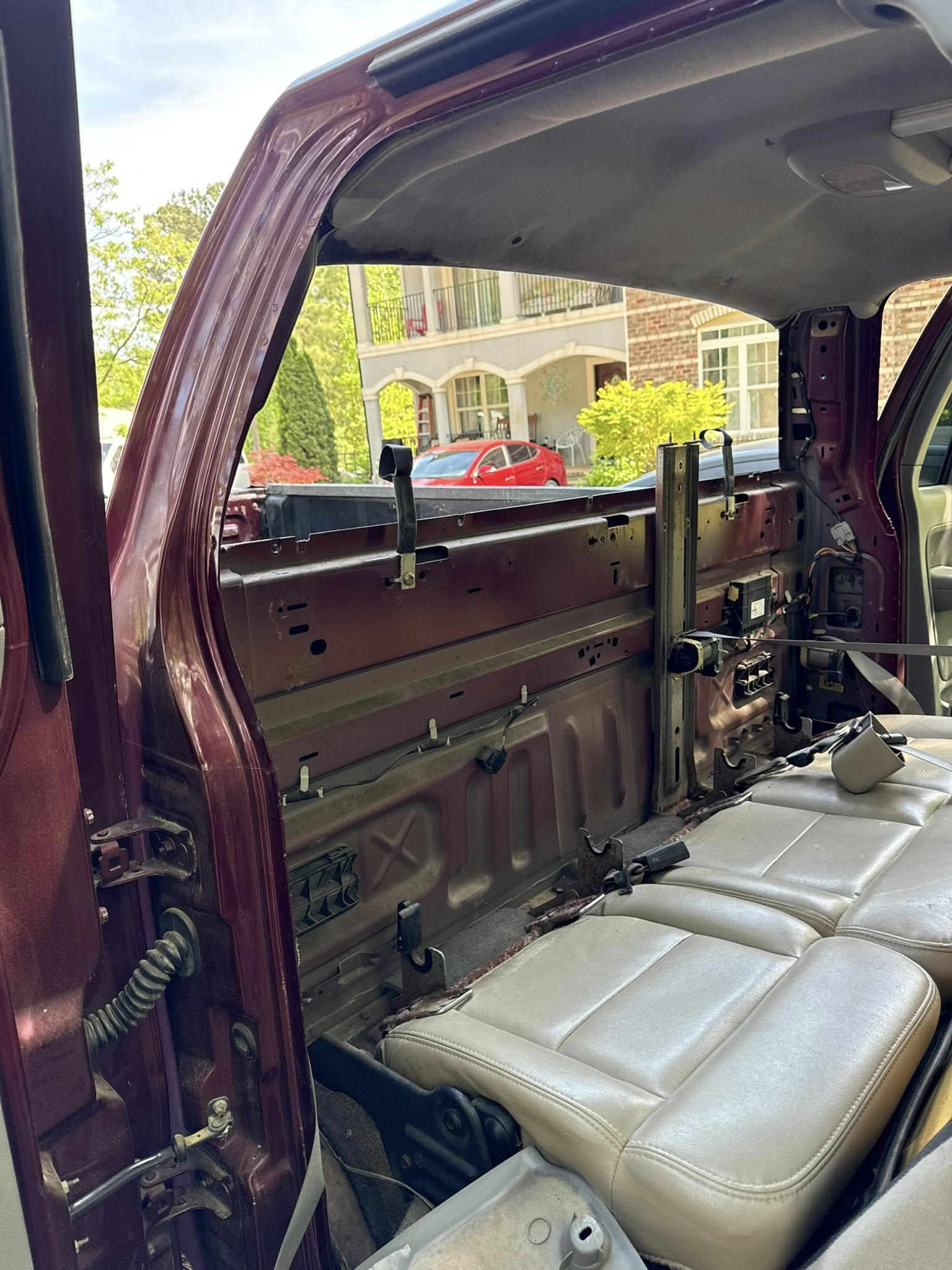 Open side door of a maroon van showing a folded wheelchair lift and beige seats inside