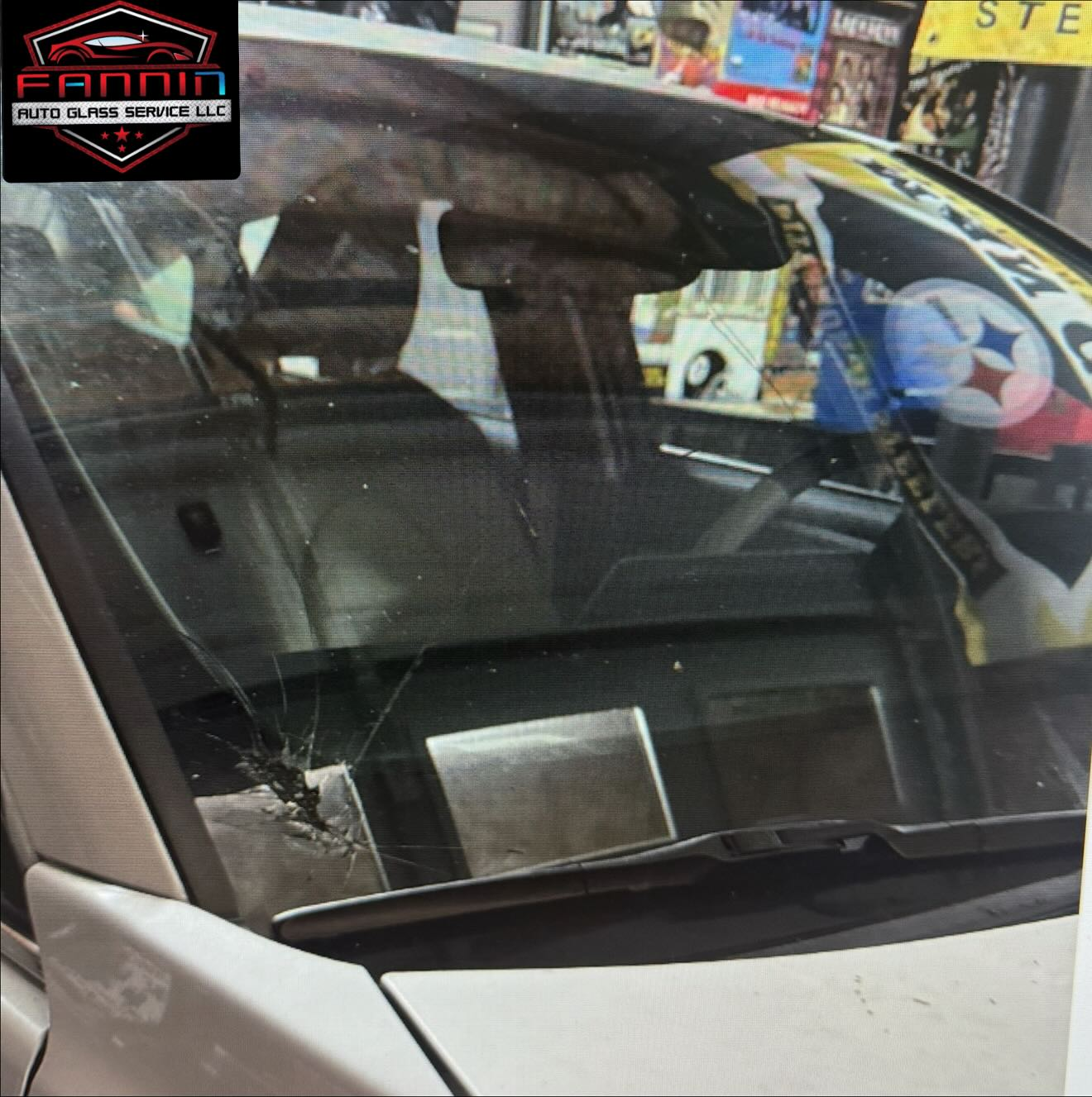 Close-up of a car windshield with reflections and a visible cracked lower-left corner.