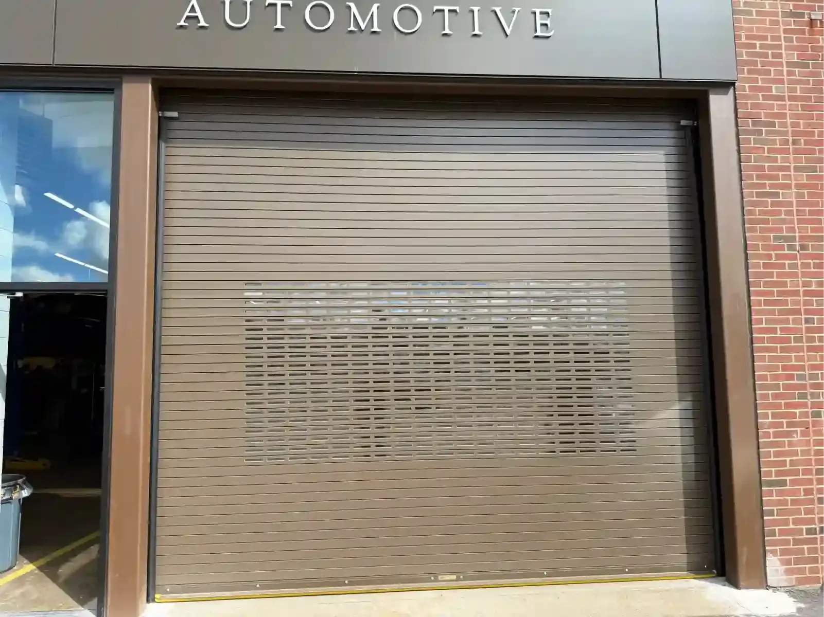 Closed beige roller shutter on an automotive shop storefront