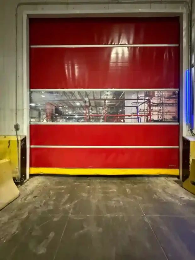 Red industrial roll-up door with a clear strip window in a warehouse loading area