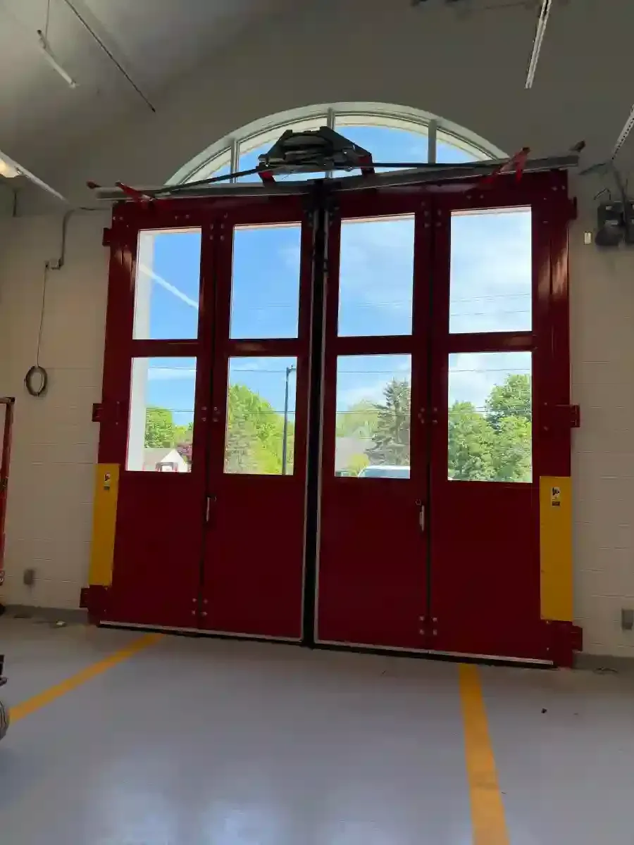 Red double doors with windows in a garage bay, framed by yellow safety markings.